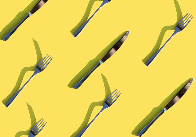 forchetta e coltello su uno sfondo giallo brillante posate con ombre dure