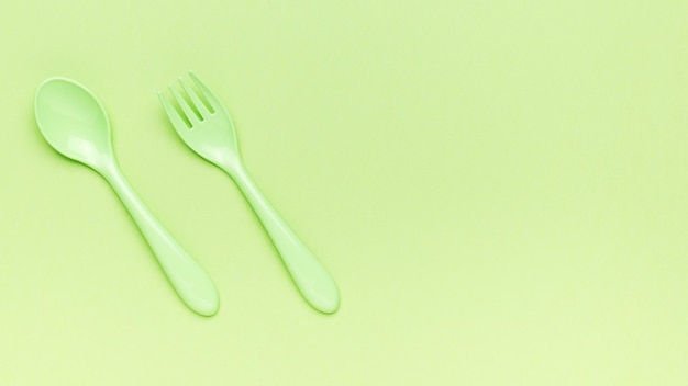 Forchetta e cucchiaio verde su sfondo verde Un posto per il testo Piatto lay