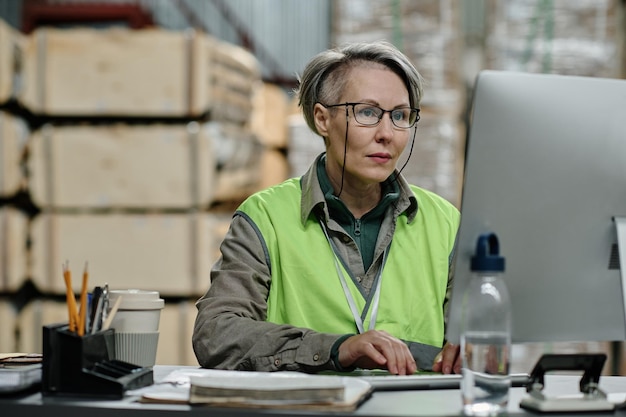 Foreman con gli occhiali che si concentra sul suo lavoro online sul posto di lavoro che controlla la posta elettronica sul computer