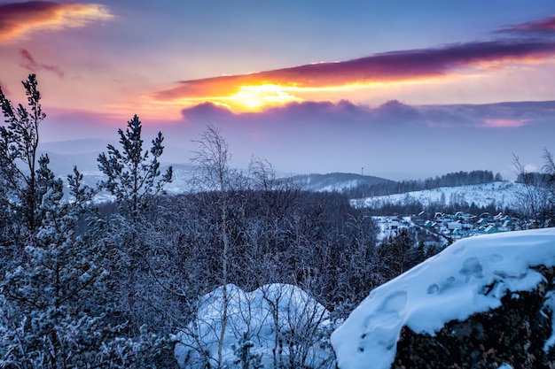 Foresta e villaggio d'inverno al tramonto