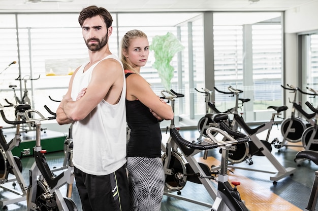 Forma coppia in piedi schiena contro schiena con le braccia incrociate in palestra