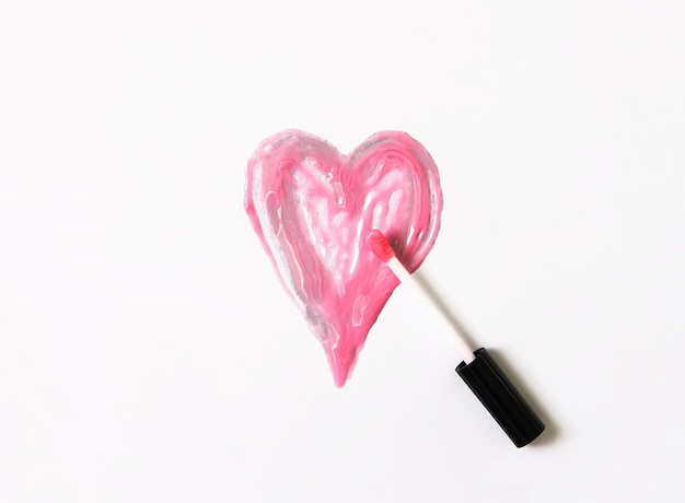 Forma del cuore disegnata a mano. Campione di lucidalabbra rosa su sfondo bianco.