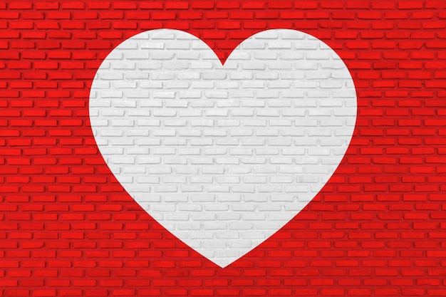 Forma di cuore bianco sul muro di mattoni rossi