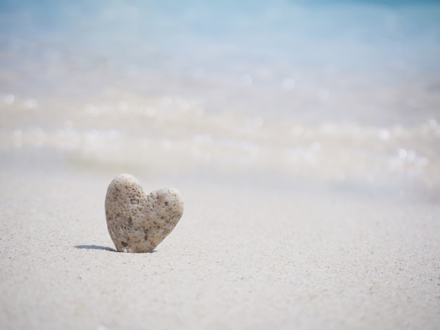 Forma di pietra del cuore che sta sulla sabbia della spiaggia di estate