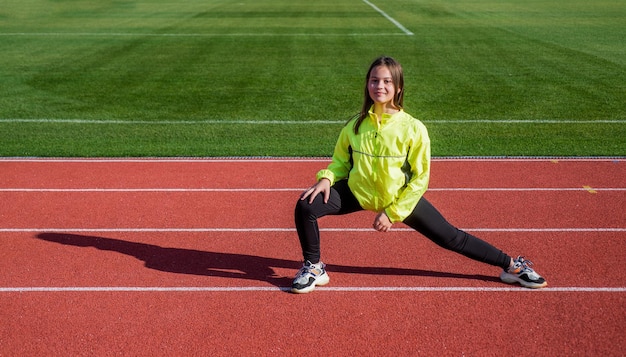 Forma fisica di addestramento della ragazza del bambino sano sulla pista da corsa dello stadio, successo sportivo.