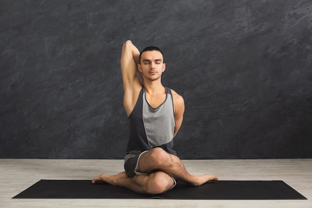 Forma fisica, yoga flessibile di addestramento dell'uomo nella posa della testa della mucca. Ragazzo sportivo che fa schiena e spalle che si allungano in palestra, copia spazio