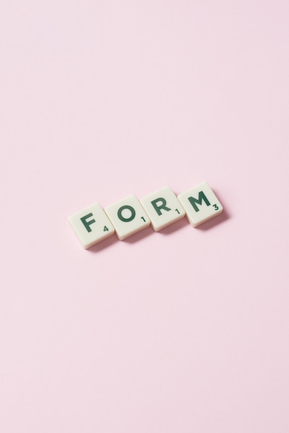 Forma formata da piastrelle scrabble su sfondo rosa