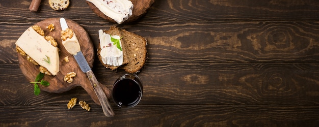 Formaggi assortiti su piastra di legno, pane e vino