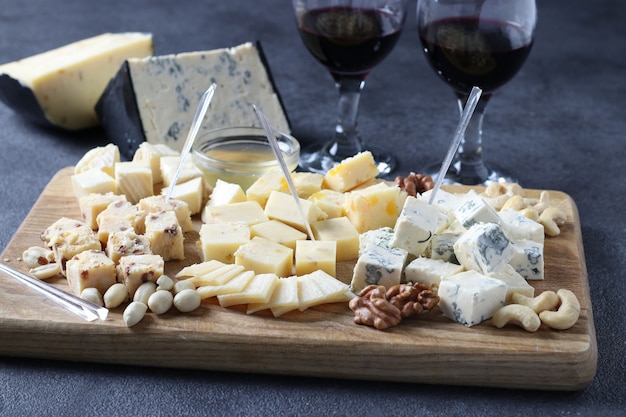 Formaggi d'élite: con tartufo, dor blue, brie, parmigiano e assortimento di noci su tavola di legno. Antipasto per una festa del vino