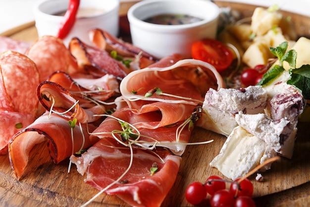 Formaggi e salumi con salse e frutti di bosco su una tavola di legno con profondità di campo ridotta