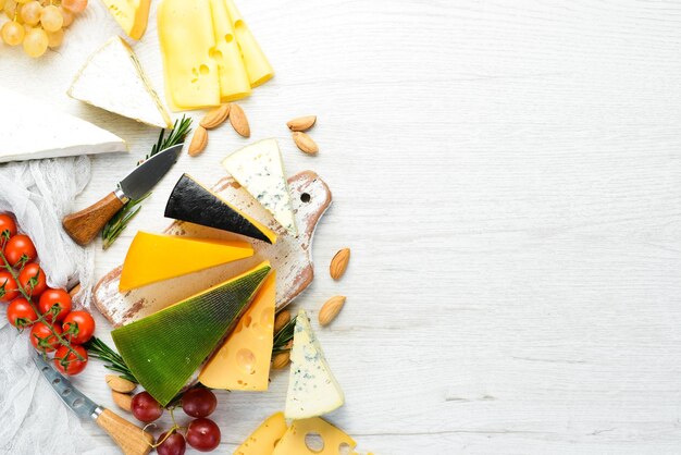 Formaggi e snack assortiti su fondo di legno bianco Prodotti lattiero-caseari Vista dall'alto Spazio libero per il testo