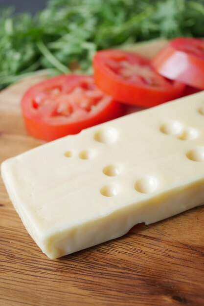 Formaggio a fette con fori su un tagliere sul tavolo