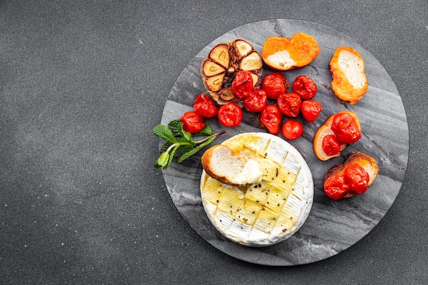 Formaggio a pasta molle al forno Brie o Camembert pomodoro aglio ed erbe pasto cibo spuntino sul tavolo