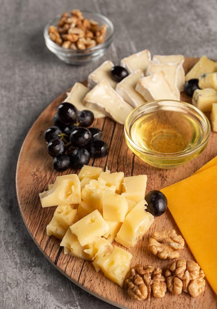 Formaggio assortito su un piatto di legno su sfondo grigio