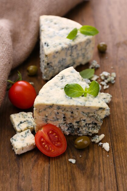 Formaggio blu saporito con olive di pomodoro e basilico su tavola di legno