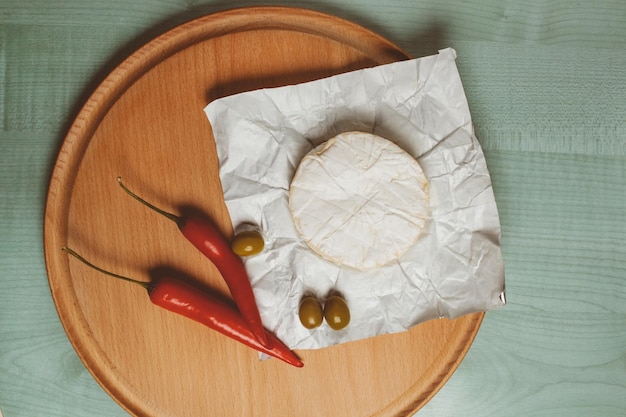 formaggio brie camembert olive verdi peperoncino su sfondo di legno chiaro elaborazione di foto d'epoca