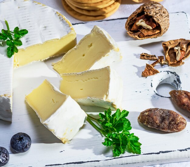 Formaggio Camembert affettato su una tavola di legno bianca