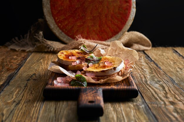 Formaggio Camembert al forno con pane tostato su tavola di legno.