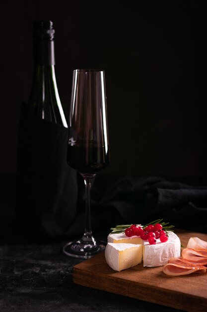 Formaggio Camembert decorato con ribes rosso su una tavola di legno e vino rosso