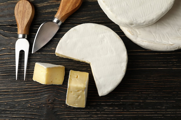 Formaggio Camembert e coltelli su sfondo di legno, vista dall'alto