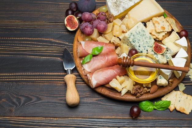 Formaggio Camembert e prosciutto con miele, fichi, noci su tavola di legno