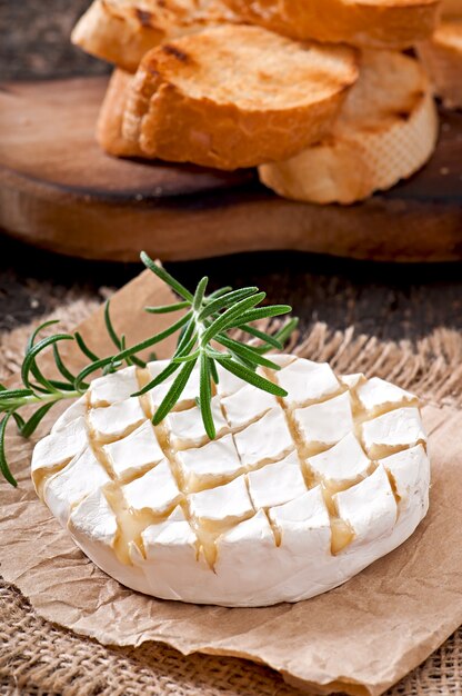 Formaggio Camembert e un rametto di rosmarino su un tavolo di legno