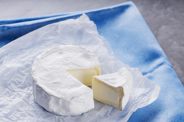 Formaggio Camembert sul tovagliolo blu. Formaggio bianco sulla superficie del cemento. Copia spazio