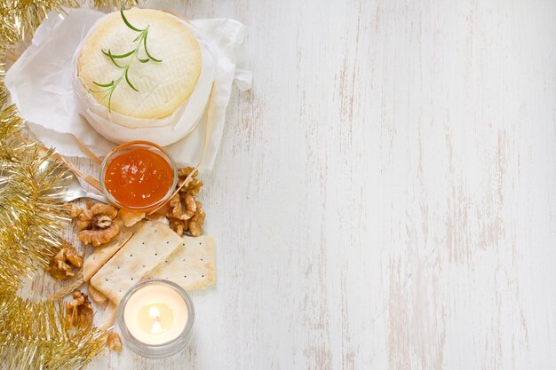 Formaggio con marmellata di zucca e biscotti su superficie di legno bianco