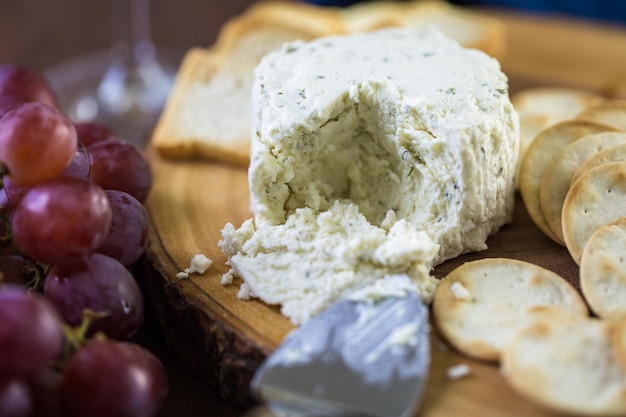 Formaggio cremoso dal sapore morbido con aglio ed erbe fini su una tavola di legno con cracker.