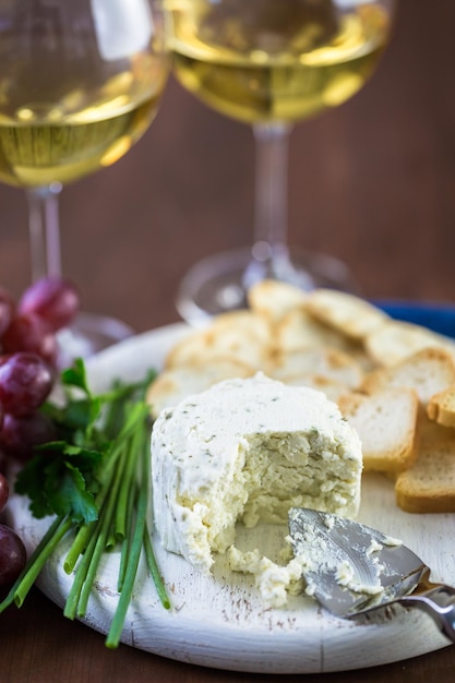 Formaggio cremoso dal sapore morbido con aglio ed erbe fini su una tavola di legno con cracker.