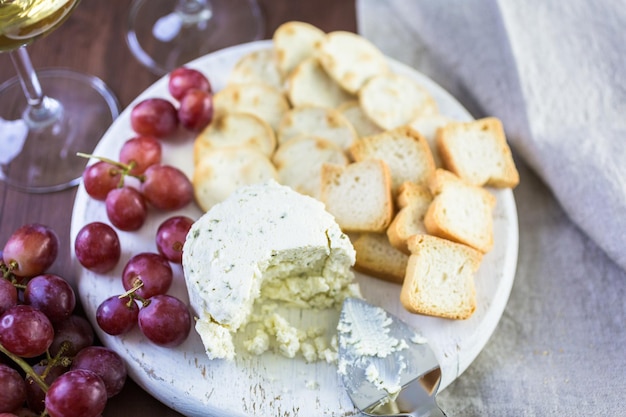 Formaggio cremoso dal sapore morbido con aglio ed erbe fini su una tavola di legno con cracker.