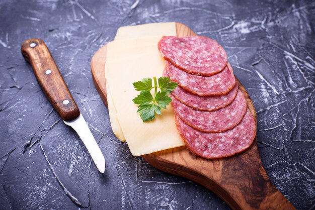 Formaggio e salame a fette su tavola di legno