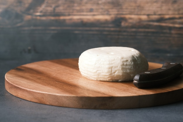 Formaggio fresco di forma rotonda su un tagliere sul tavolo