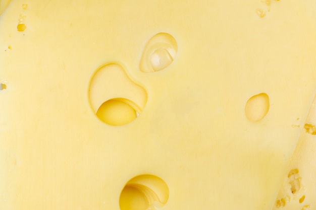 Formaggio giallo con sfondo di fori. Consistenza del formaggio. Primo piano, foto macro.