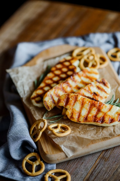 Formaggio Halloumi fritto con rosmarino su un tagliere di legno sul tavolo di legno con piccole salatini