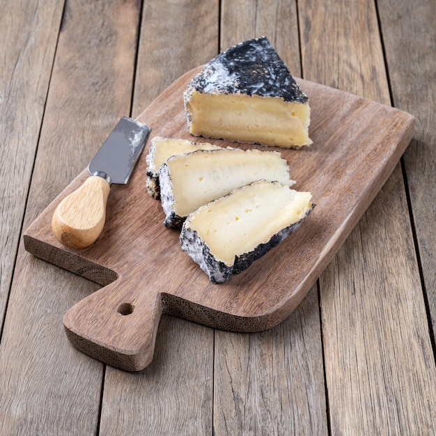 Formaggio invecchiato al carbone con fette su tavolo di legno