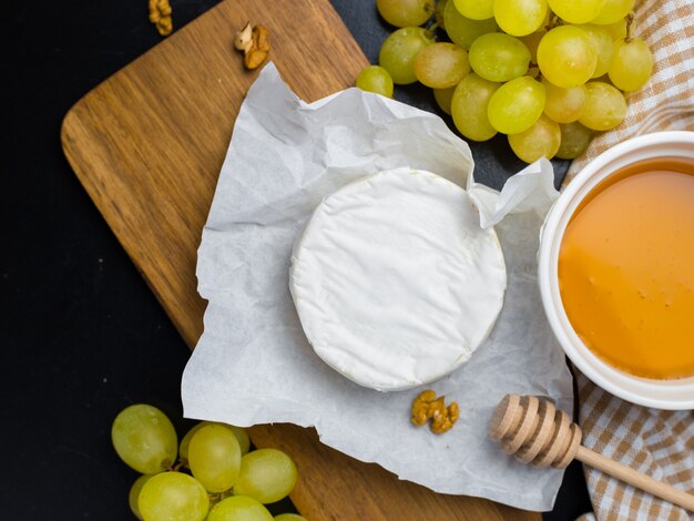 Formaggio morbido. Camembert, miele e uva su un legno con noci.