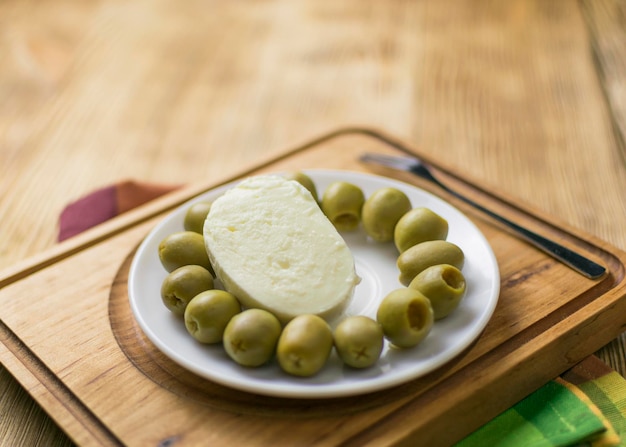 Formaggio mozzarella e olive su un piatto su un fondo di legno