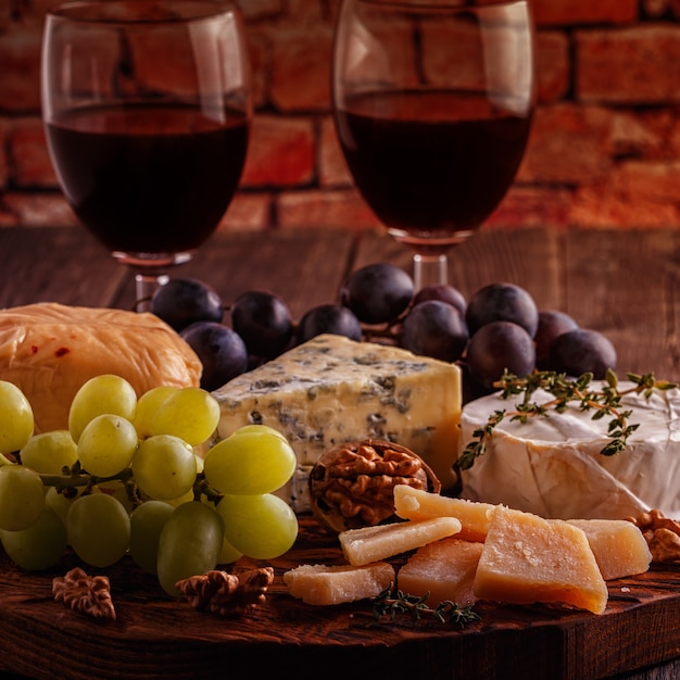 Formaggio, noci, uva e vino rosso su fondo in legno