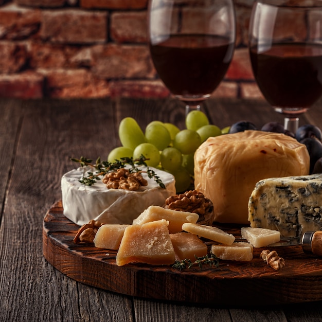 Formaggio, noci, uva e vino rosso sul tavolo di legno