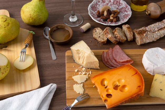 Formaggio, prosciutto, pere e pane sopra fondo di legno