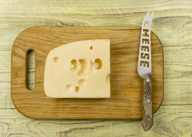 Formaggio sul tagliere e coltello su fondo di legno