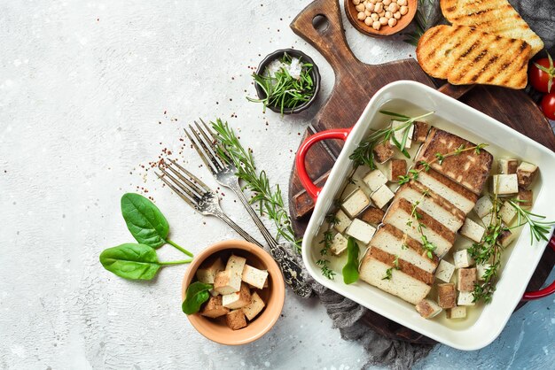 Formaggio Tofu Formaggio Tofu al forno con rosmarino e spezie in una ciotola Su uno sfondo di pietra