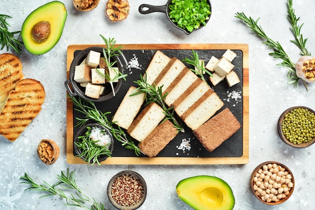 Formaggio tofu fresco Formaggio tofu affumicato con spezie tagliate a pezzi su una tavola Cibo sano vegano su uno sfondo di pietra