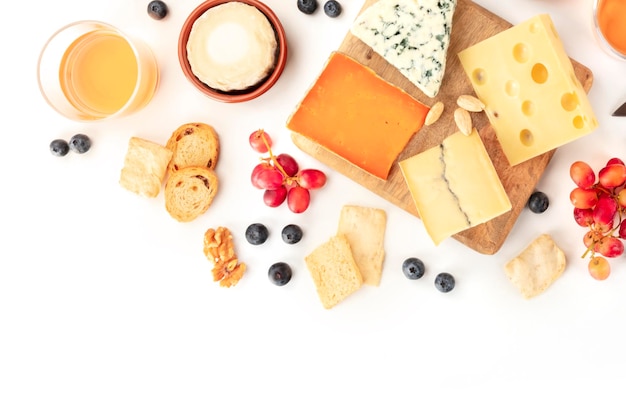 Formaggio un piano a terra girato su uno sfondo bianco con spazio di copia Formaggio blu Leicester Emmental e altri tipi con vino frutta noci e un posto per il testo