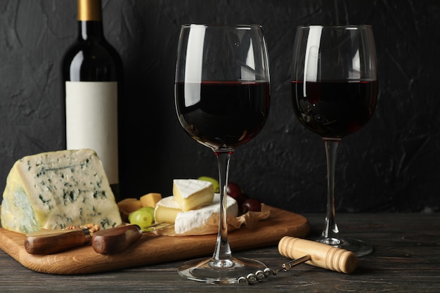 Formaggio, uva, bottiglia e bicchieri con vino su legno