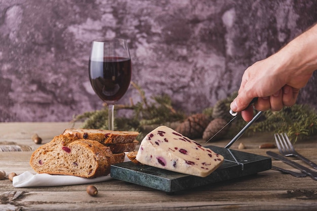 Formaggio Wensleydale con mirtilli rossi vino miele noci uvetta su tagliere di legno Sfondo di cemento nero Messa a fuoco selettiva