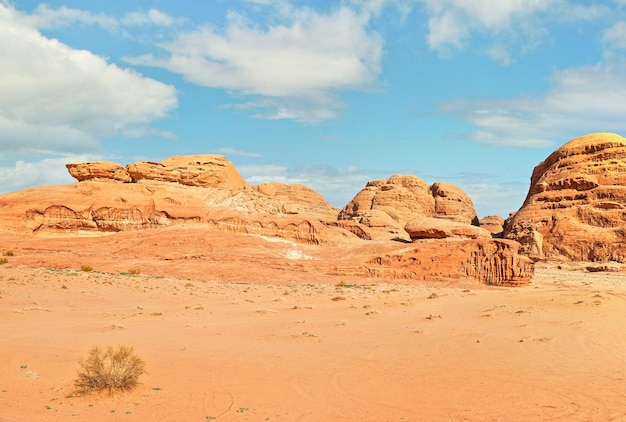 Formazioni rocciose e montagne nel deserto sabbioso, cielo blu sopra, scenario tipico di Wadi Rum, Giordania.