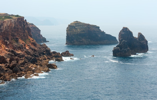 Formazioni rocciose vicino alla riva. Vista nebbiosa della costa rocciosa atlantica di estate (Costa Vicentina, Algarve, Portogallo).