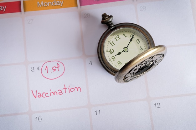 Formulazione Vaccinaton sul calendario con orologio da tasca vintage, appuntamento per la salute.